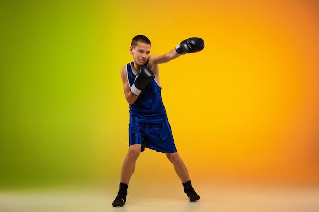 Фото Подростковый боксер на фоне градиентной неоновой студии в движении ногами, боксом