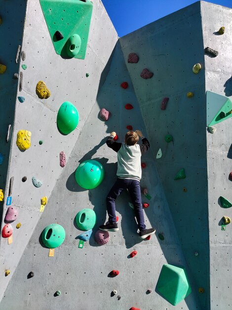 A teenage boy climbs the wall to climb the hooks View from below