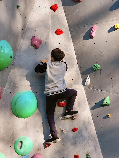 A teenage boy climbs the wall to climb the hooks View from below