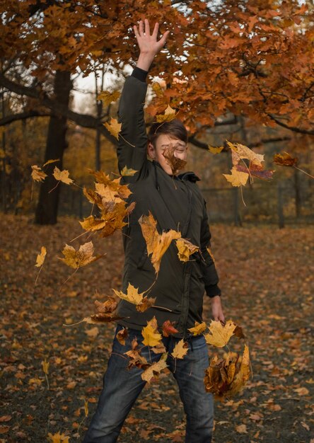 Photo teenage boy falling leaves in park during autumn