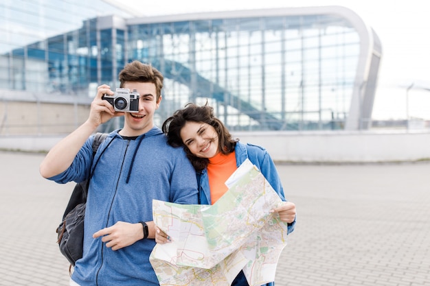 Teenage boy and girl walking around the city with a map and camera in their hands
