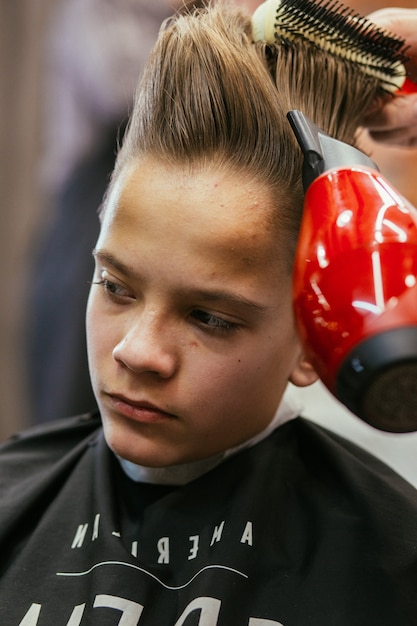 Teenage boy haircuts hairdresser in the Barber shop. Fashionable stylish retro hairstyle. Portrait of a child with a beautiful haircut. Russia, Sverdlovsk, February 12, 2019