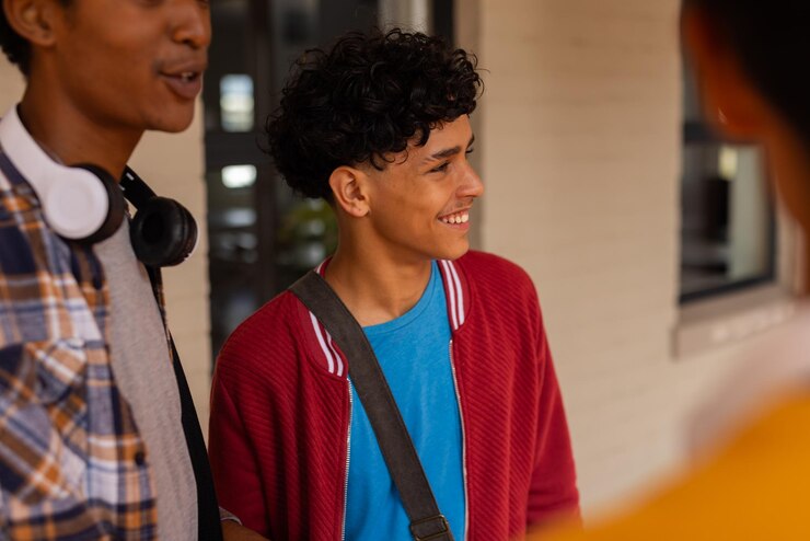 Photo teenage boy in high school smiling and talking with friends wearing casual clothes