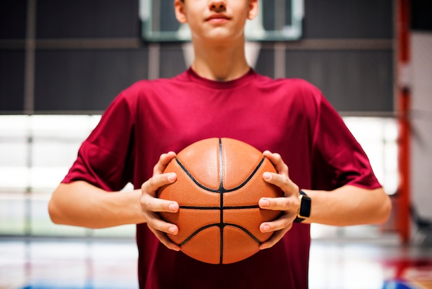 Adolescente che tiene una pallacanestro sulla corte