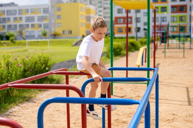 A teenage boy is engaged on horizontal bars near the school