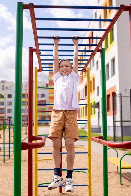 A teenage boy is engaged on horizontal bars near the school