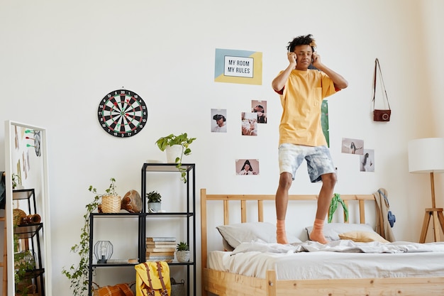 Photo teenage boy jumping on bed