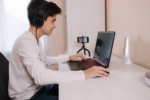 Photo teenage boy playing game on his pc computer in white room