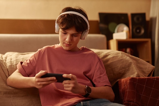 Photo teenage boy playing mobile games using smartphone