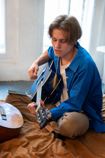 Teenage boy recording music with his guitar at his home studio