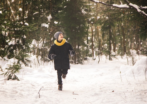 A teenage boy runs through the winter forest.