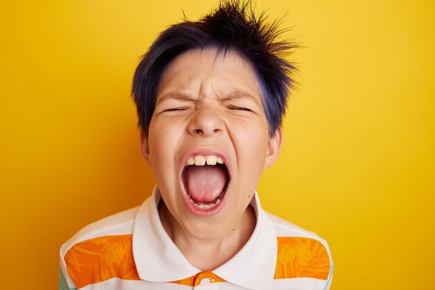 Teenage boy screaming over isolated light yellow background