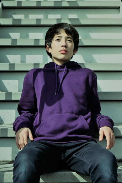 階段の向こうに座っている十代の男の子