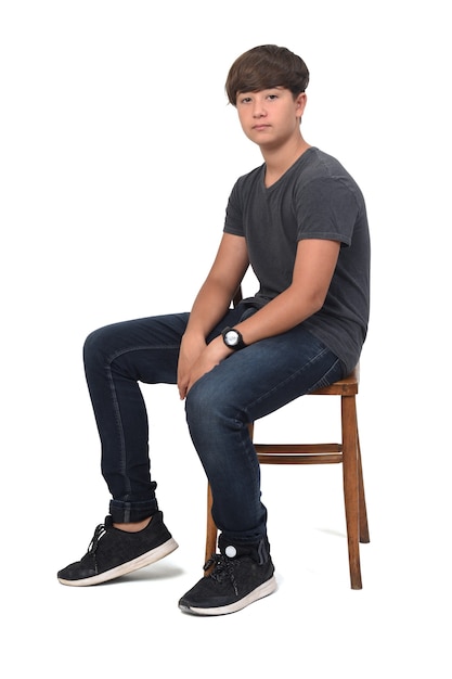 Teenage boy sitting on a chair with white , serious and 