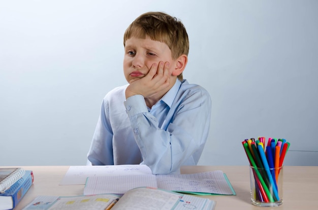 Photo a teenage boy sitting at a desk in class is bored