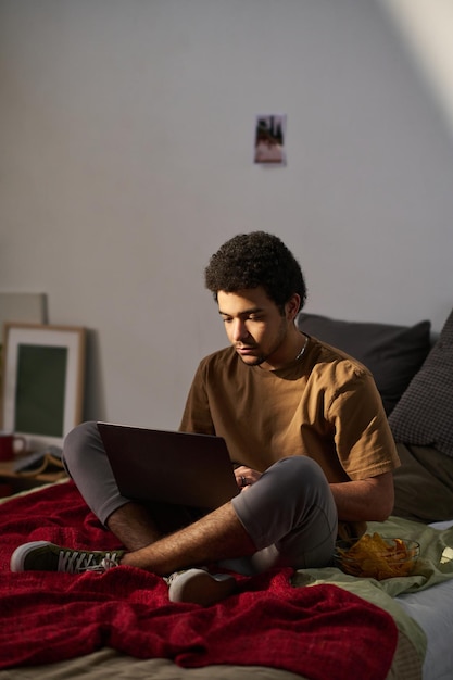 Teenage boy using laptop in his bedroom