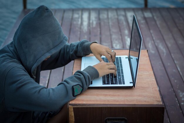 Teenage boy using laptop while sitting at table on wooden pier