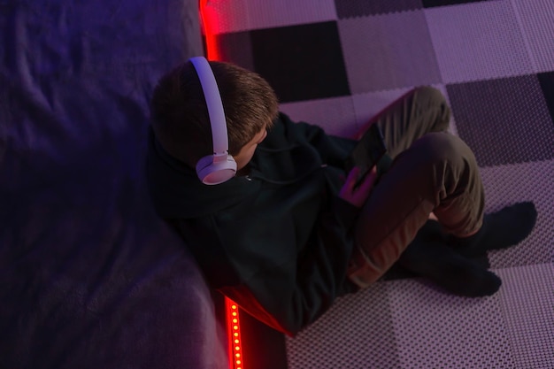 Teenage boy using phone in his room with neon light