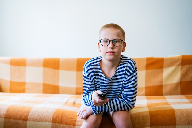 A teenage boy watches tv using remote control to change\
channels young man is unhappy with what he s...