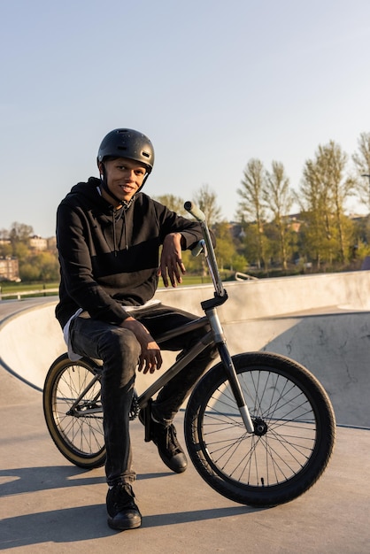 写真 ヘルメットをかぶった10代の少年は、屋外でスポーツをしている春の男のランプで黒いbmxローバイクに座っています