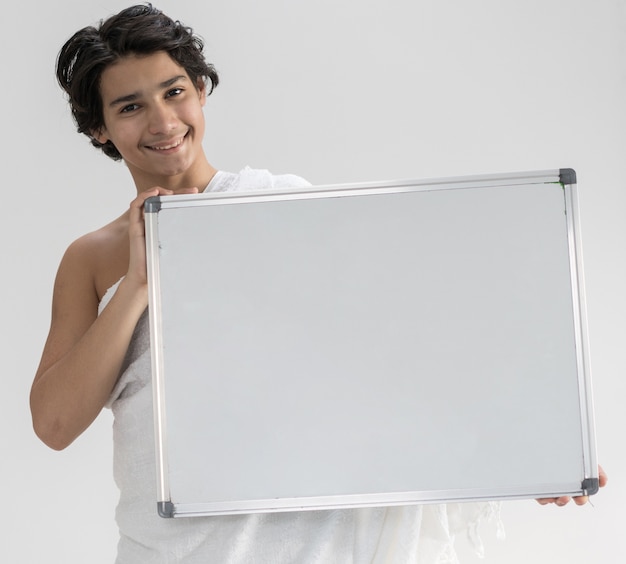 Photo teenage boy wearing ihram for hajj holding copy space board