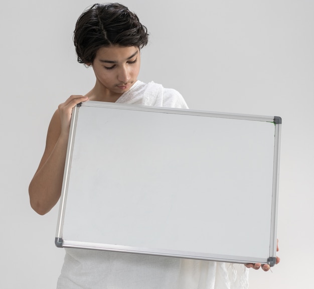 Photo teenage boy wearing ihram for hajj holding copy space board