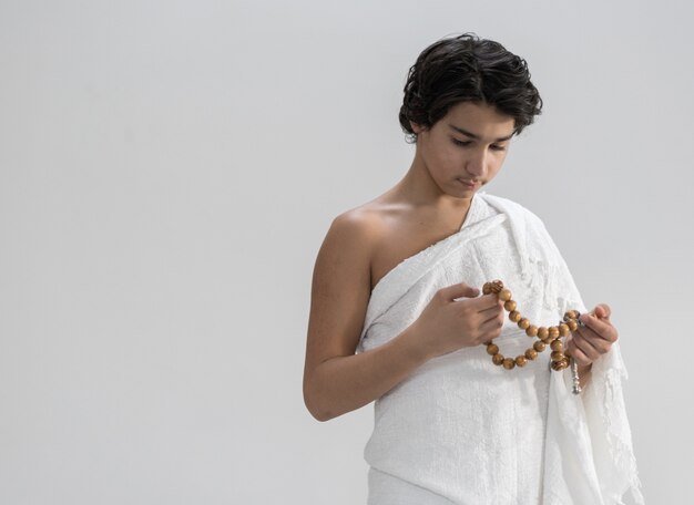 Teenage boy wearing Ihram for Hajj with rosary