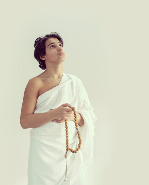 Photo teenage boy wearing ihram for hajj with rosary