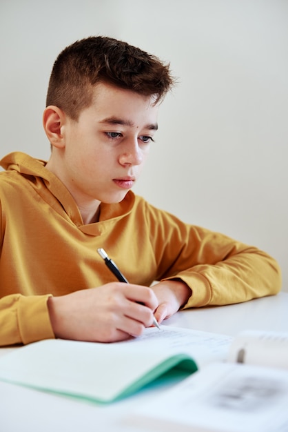 Teenage boy writes homework at home