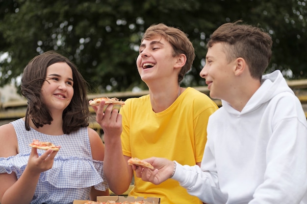 Teenage boys and a girl sharing snacks outdoors