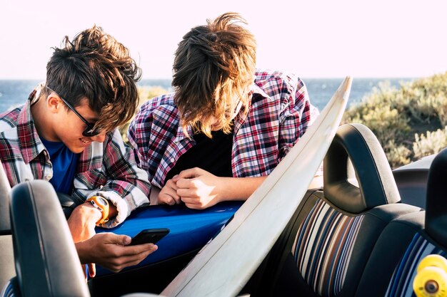 Photo teenage boys using mobile phone outdoors