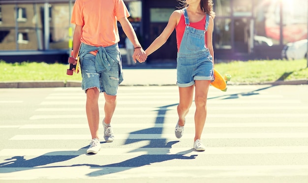 Photo teenage couple with skateboards on city crosswalk