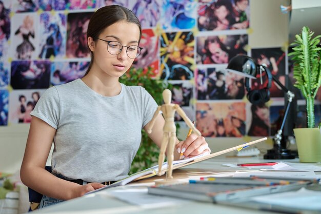 집에 있는 테이블에 연필로 그림을 그리는 10대 창의적인 소녀 예술가
