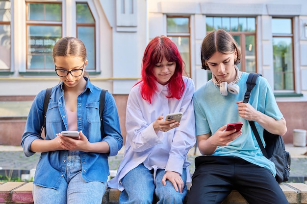 Amici adolescenti insieme all'aperto per divertirsi utilizzando gli smartphone