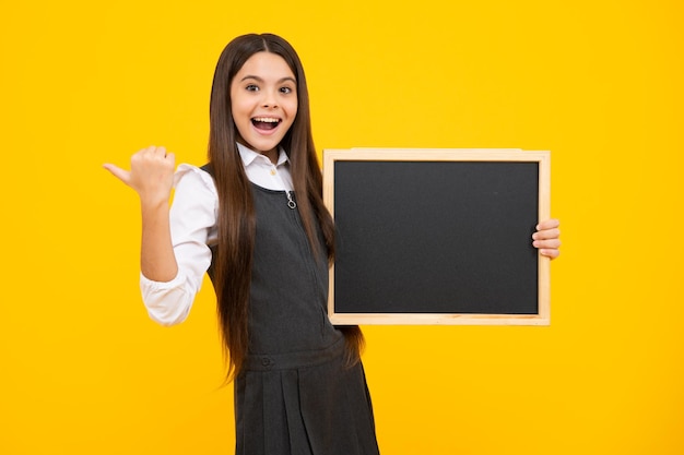 10代の少女の子供が黒板を持っている空白の黒板のチョークボードを持っている小学生の女の子