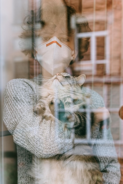 девочка-подросток вьющиеся волосы грустные карие глаза защитная медицинская маска с серым пушистым котом на руках смотрит