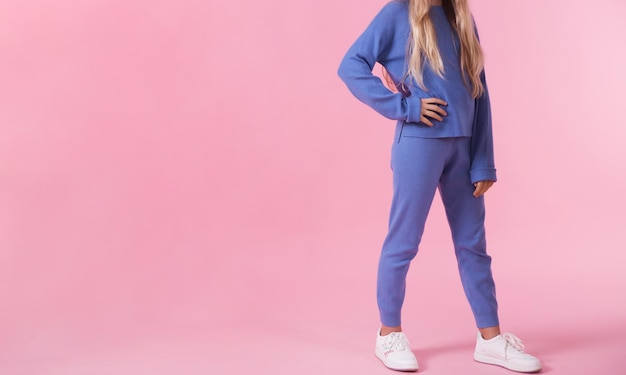 A teenage girl demonstrates a blue tracksuit on a blue background