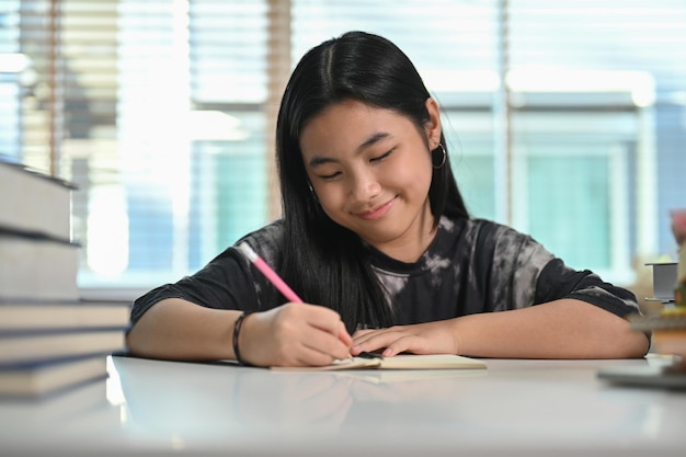 Девочка-подросток делает домашнее задание в гостиной Концепция образования и школы