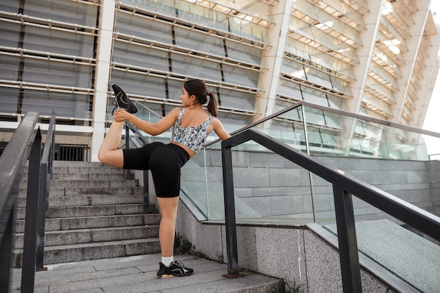 Teenage girl doing sports and stretching exercises outdoor of the city background