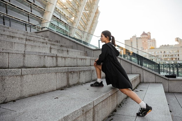 Teenage girl doing sports and stretching exercises outdoor of the city background