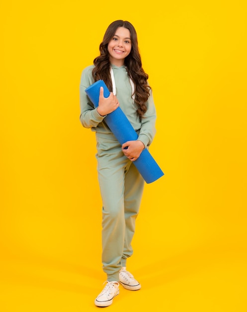 Teenage girl dressed in sports uniform posing in the studio child in a posh stylish sports suit in a hoodie with a hood advertising sportswear and yoga wear healthy kids lifestyle sport