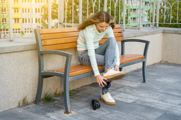 Photo teenage girl dresses wheels on sneakers