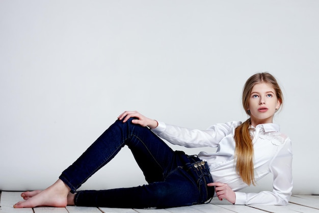 Teenage girl on the floor posing against grey background