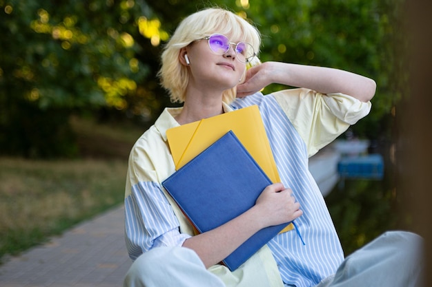 Teenage girl in glasses with colorful folders outsideCloseup portrait