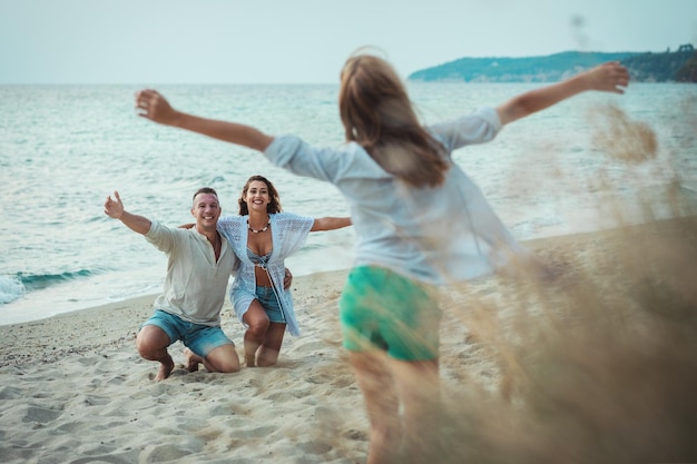 Teenage girl and her parents are playing on the beach. A girl runs to her parents in a hug.