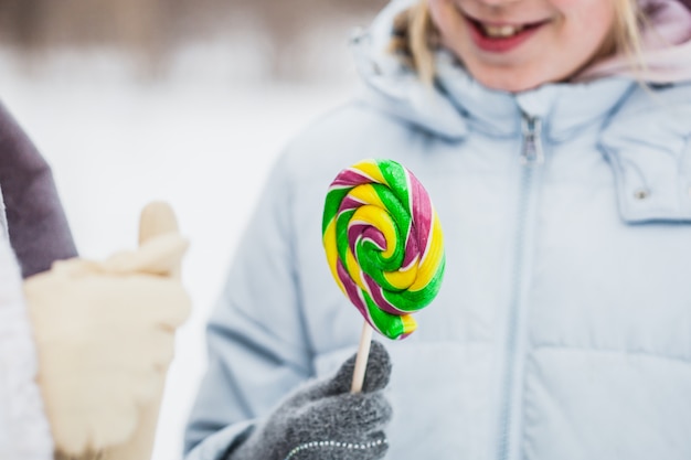 Teenage girl holding a lollipop in the winter