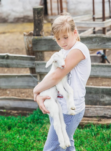 teenage girl holding a small goat at the farm