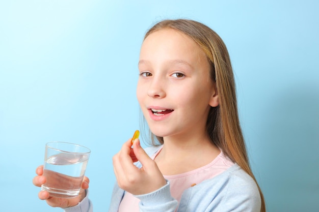 A teenage girl holds an omega  capsule in her hands on a colored background