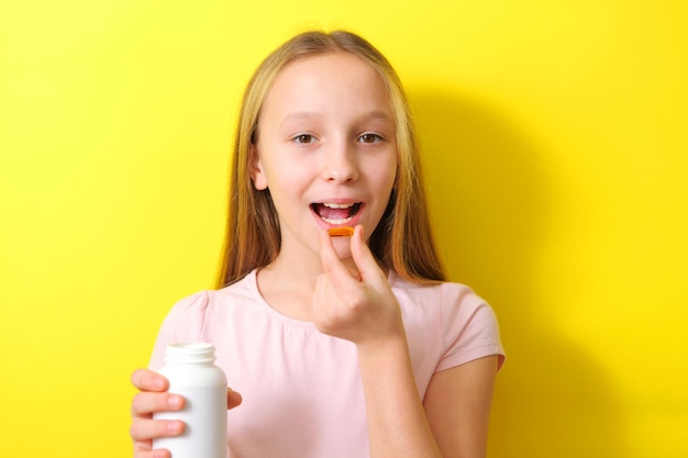 A teenage girl holds an omega capsule in her hands on a colored background