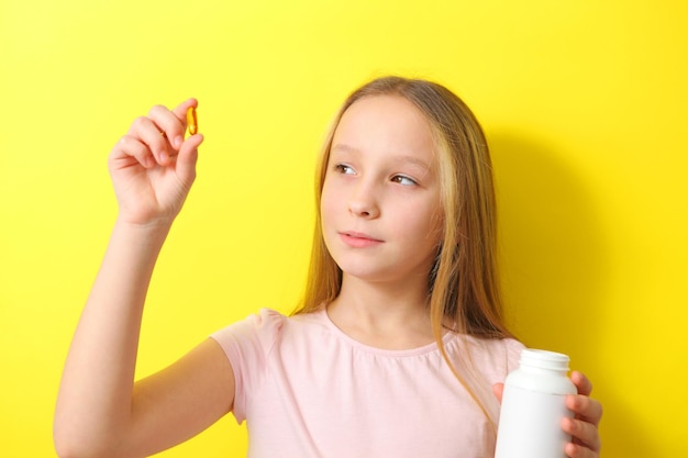 Foto una ragazza adolescente tiene in mano una capsula omega su uno sfondo colorato